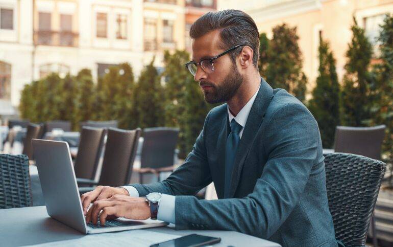 Málaga: A Growing Destination for International Investors and Entrepreneurs. Modern businessman. Portrait of handsome bearded businessman in eyeglasses working with laptop while