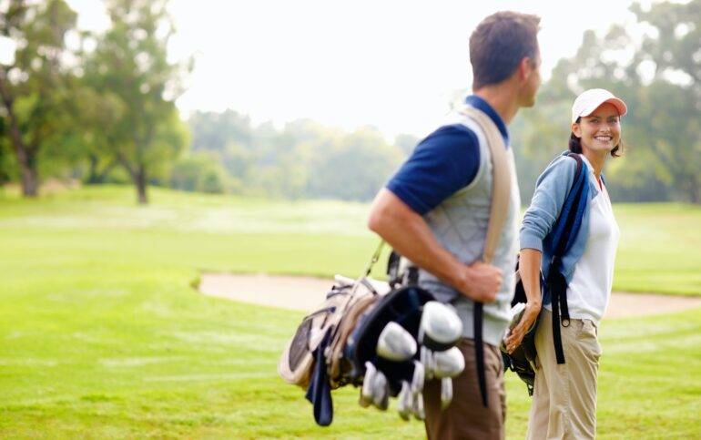 Golf in Marbella. Female golfer smiling and looking at man. Focus on female golfer smiling and looking at man.