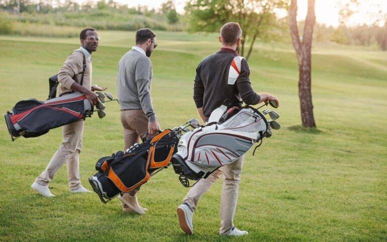 Clubes de golf en la Costa del Sol. Jugadores de golf multiétnicos con palos de golf en bolsas caminando por el campo de golf.