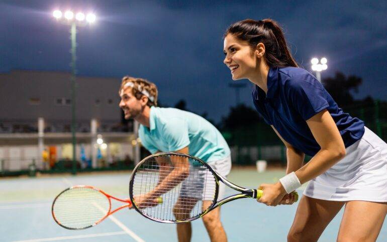 Sports Events in Marbella. Tennis sport people concept. Mixed doubles player hitting tennis ball with partner standing near net