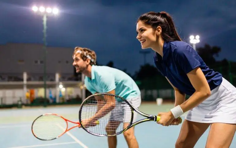 Sports Events in Marbella. Tennis sport people concept. Mixed doubles player hitting tennis ball with partner standing near net