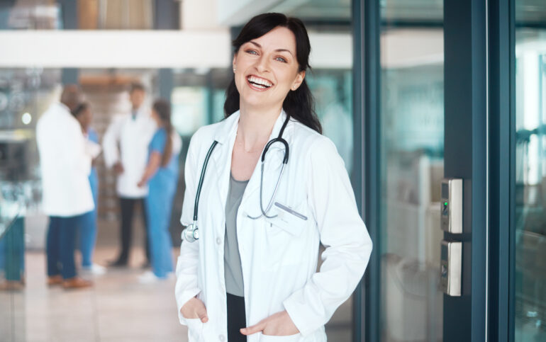 Atención médica en Marbella. Retrato de una doctora segura de sí misma trabajando en un hospital con sus colegas al fondo.