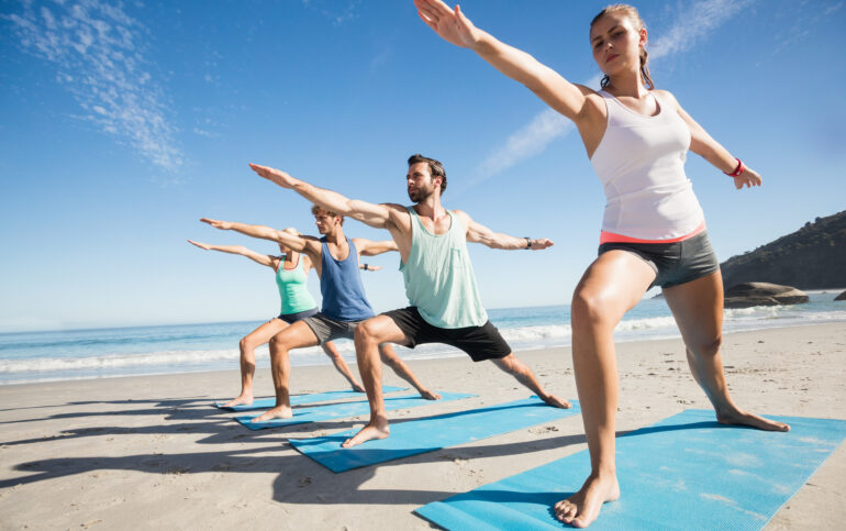 Vive en Marbella y encuentra tu serenidad en la playa con el yoga. Gente haciendo yoga en la playa